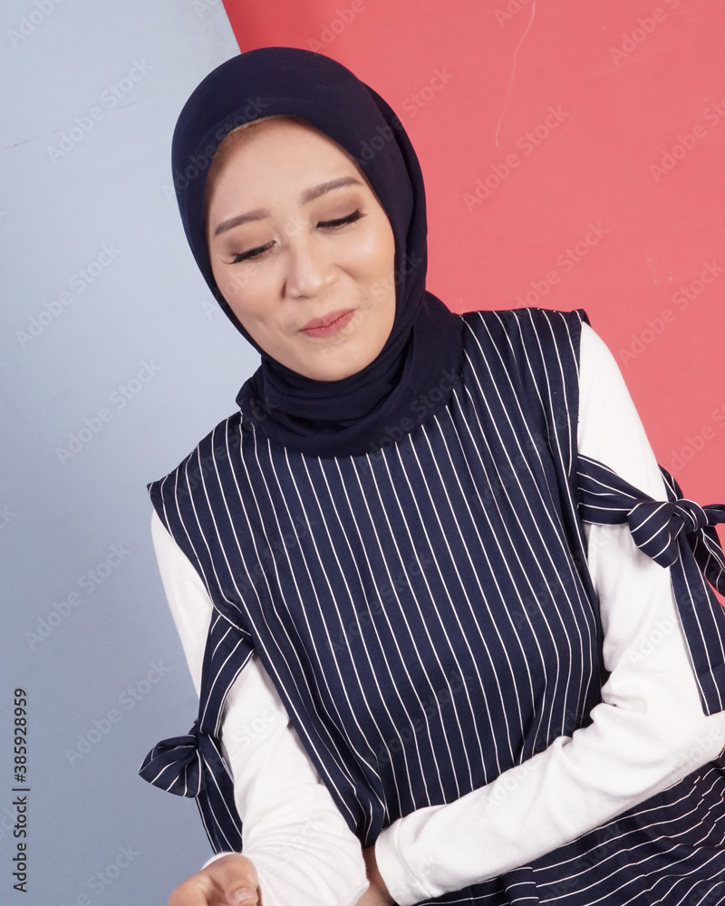 women in hijab are posing like famous models. The woman is wearing a blue striped shirt and jeans. Indonesian hijab model. women in hijab are posing like famous models. The woman is wearing a blue striped shirt and jeans. Indonesian hijab model.
