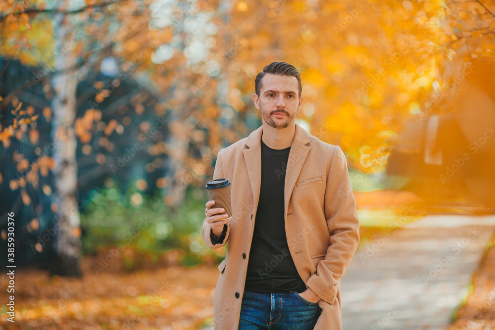 Young man drinking coffee in autumn park outdoors Young man drinking coffee in autumn park outdoors