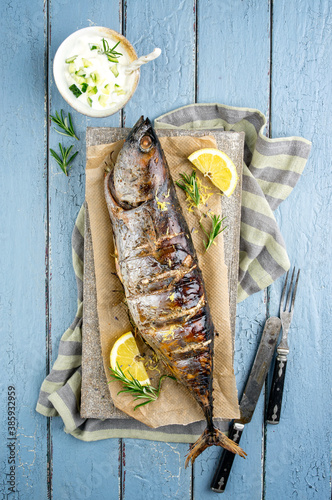 Traditional Australian barbecue bonito fisch with tzatziki and lemon slices offered as top view on a rustic wooden board photo