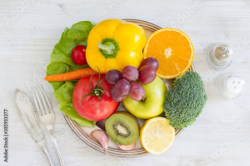 Fototapeta Naklejka Na Ścianę i Meble -  Plate full of fruits and vegetables, cutlery, spices. Healthy meal concept