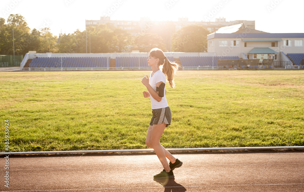 Active young woman jogging at the stadium