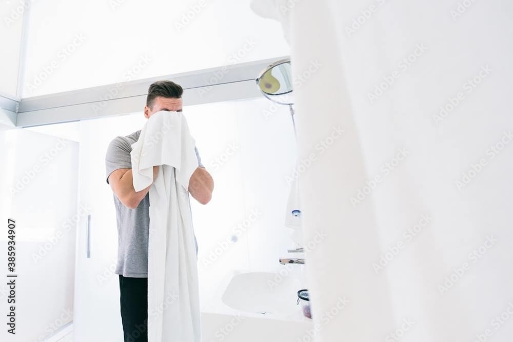 a man wipes himself with a white towel after washing his face