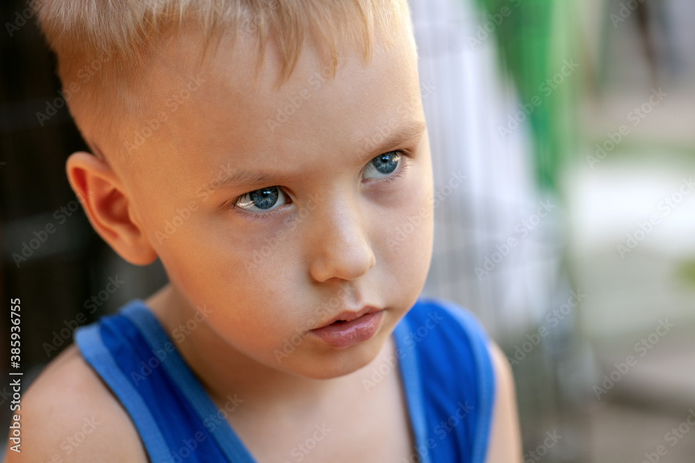 Close up portrait of beautiful baby boy with very serious look. Blond hair, blue eyes, strong emotions, sad face expression. Outdoors, copy space. Close up portrait of beautiful baby boy with very serious look. Blond hair, blue eyes, strong emotions, sad face expression. Outdoors, copy space.
