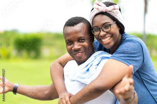African American couple in love smiling and looking at camera outdoors at park