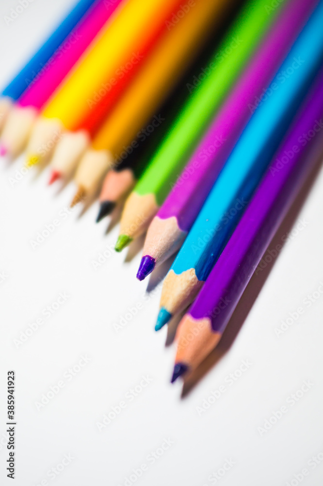 Naklejka premium Colored pencils for drawing, well sharpened, lie in a row on a white background.