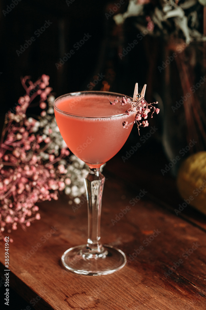 Elegant red cocktail with flowers on the background.