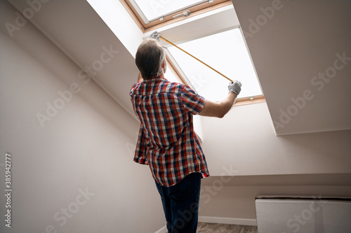 Foto Rear view of repairman measuring skylight window