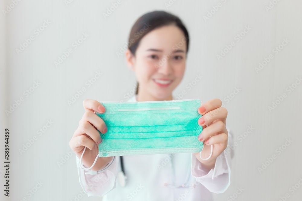 Asian woman hold a medical face mask to show that we have to wear its to protect respiration system from pollution and virus (Covid 19). Health and Corona virus concept. Asian woman hold a medical face mask to show that we have to wear its to protect respiration system from pollution and virus (Covid 19). Health and Corona virus concept.