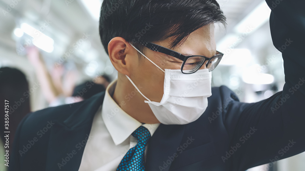 Young man wearing face mask travels on crowded subway train . Coronavirus disease or COVID 19 pandemic outbreak and urban lifestyle problem in rush hour concept . - obrazy, fototapety, plakaty 