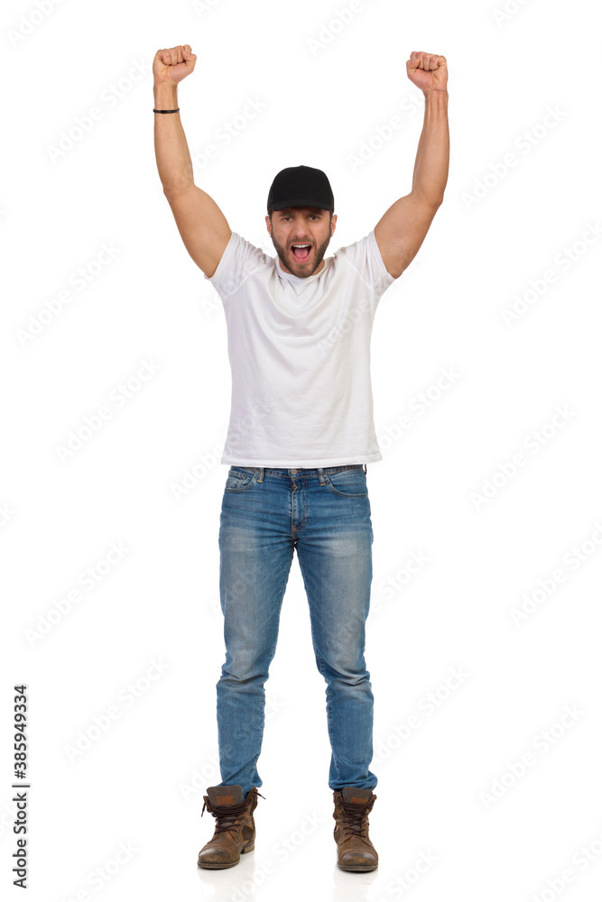 Confident Young Man Is Standing With Arms Raised And Shouting