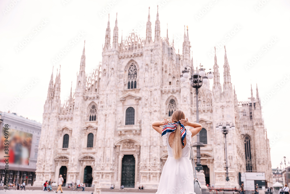 back view of a girl in a white dress straightens her headscarf a