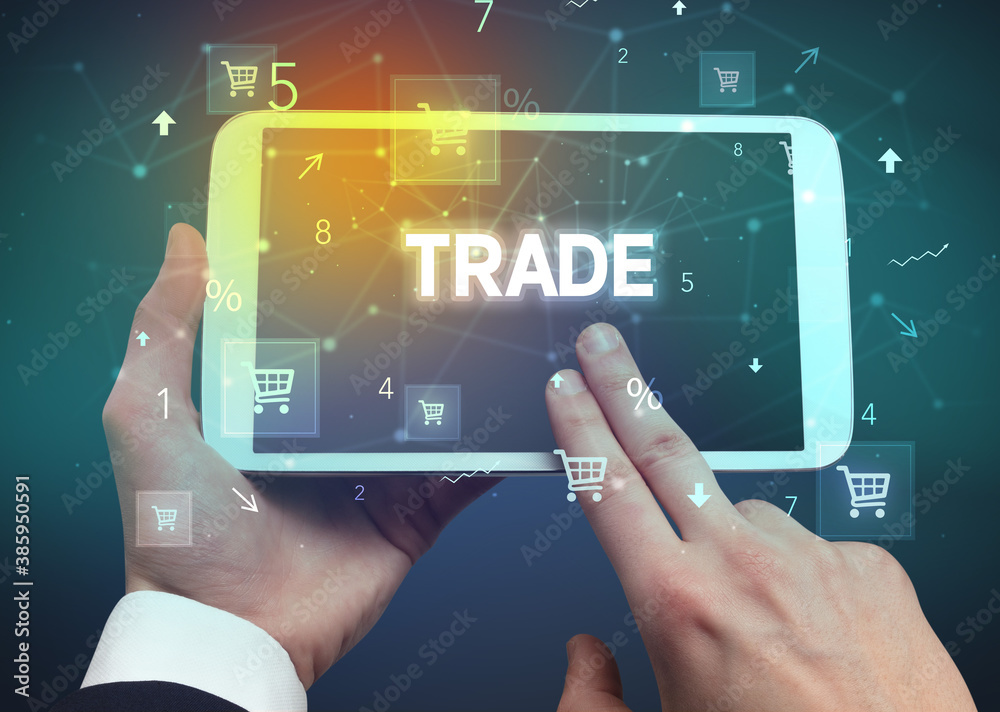 Obraz premium Close-up of a hand holding tablet with TRADE inscription, online shopping concept