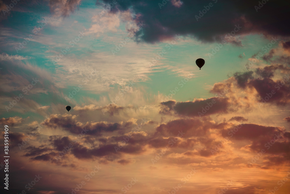 Two Hot Air Balloons fly towards the sunset.