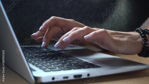 Female hands of business woman typing on laptop notebook keyboard at home office desk working online with pc software apps technology , close up side view