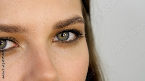 Fototapeta Naklejka Na Ścianę i Meble -  Female eyes with make-up. Pretty face with a grey eyes of an adult girl. Portrait of a beautiful young woman with fresh skin. Close-up. Attractive model looks at the camera 