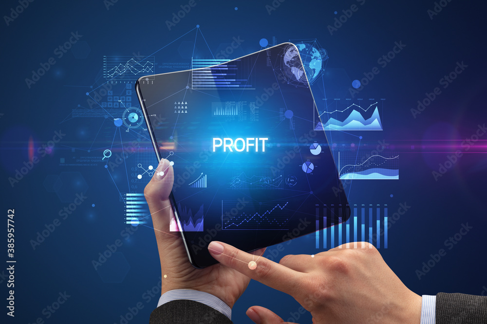 Businessman holding a foldable smartphone with PROFIT inscription, successful business concept Businessman holding a foldable smartphone with PROFIT inscription, successful business concept