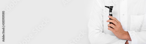 Web banner, an audiologist with otoscope on grey background. Ear treatment and hear exam photo