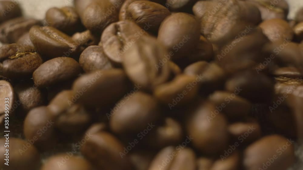 Coffee beans fall onto the fabric. Seeds of coffee fall. Quality of grain roasted coffee to spill in the bag. Coffee beans fall onto the fabric. Seeds of coffee fall. Quality of grain roasted coffee to spill in the bag.