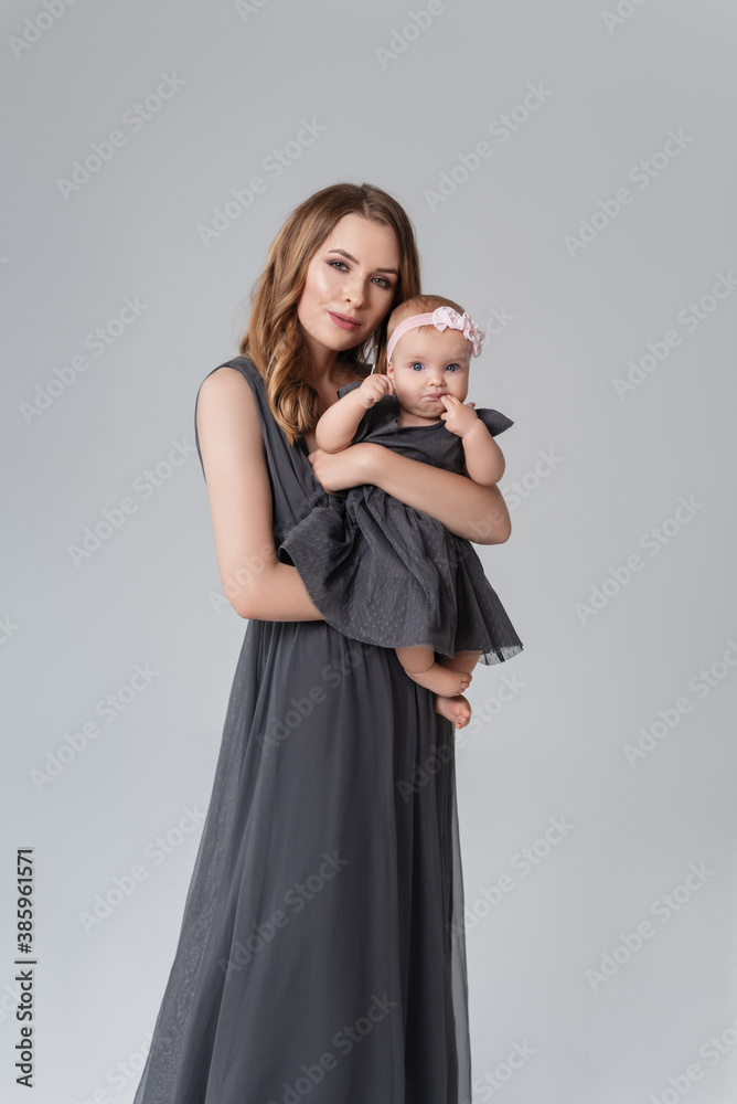 Portrait of happy mother with her baby isolated on grey.family, child and parenthood concept - happy smiling young mother with little baby at studio.Portrait of young mother and her adorable baby. Portrait of happy mother with her baby isolated on grey.family, child and parenthood concept - happy smiling young mother with little baby at studio.Portrait of young mother and her adorable baby.