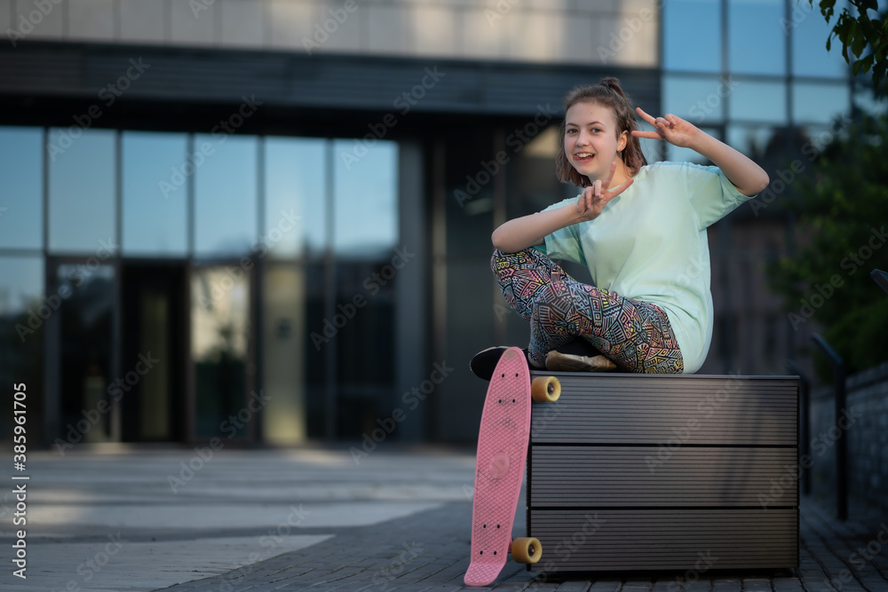 stylish teenager sit and rest with penny board after skateboarding in street