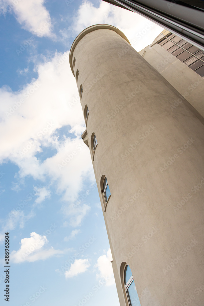 Round residential tower with windows on a background of blue sky with clouds Round residential tower with windows on a background of blue sky with clouds