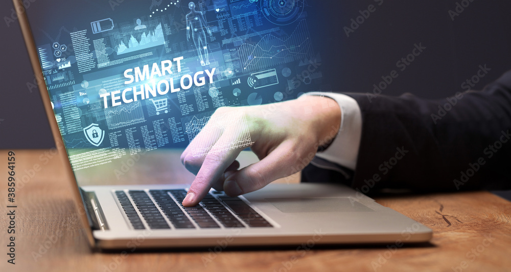Businessman working on laptop with SMART TECHNOLOGY inscription, cyber technology concept Businessman working on laptop with SMART TECHNOLOGY inscription, cyber technology concept