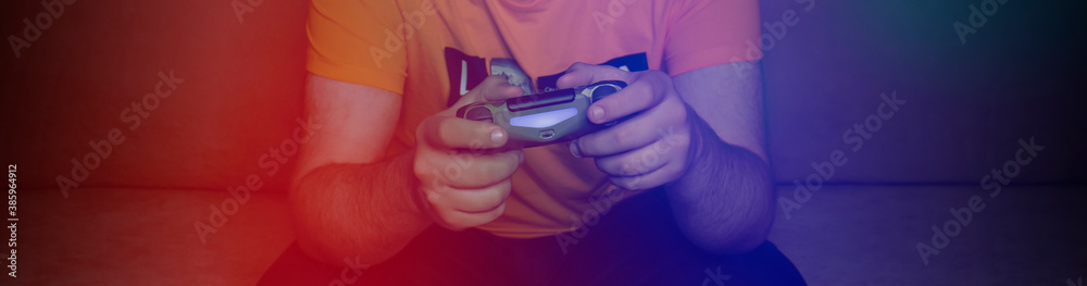 Male hands with game joystick, gamepad. The young guy is playing the console. Close up of man hands playing the video game at home. 