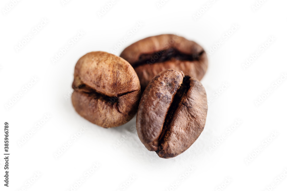 Naklejka premium Close-up of three roasted coffee beans isolated on a white background.