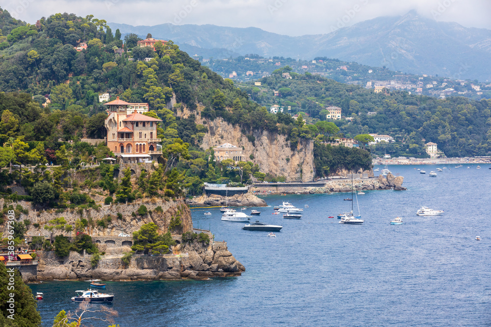 Panoramic view of the coast of Portofino and the Ligurian Sea in the Mediterranean. Trees and vegetation and some boats with tourists.