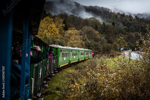 Fototapeta Naklejka Na Ścianę i Meble -  Retro Train Trough Wilderness of Bieszczady Mountains in Poland at Autumn. Dramatic Weather and Moody Toned Colors.
