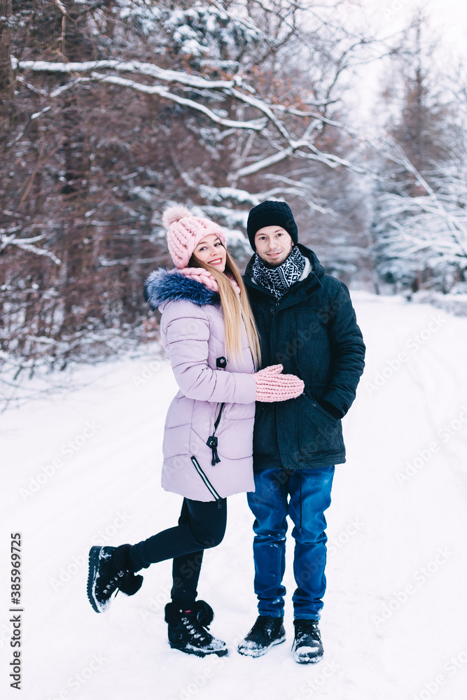 Smiling beautiful couple walking in winter park and looking at camera Smiling beautiful couple walking in winter park and looking at camera