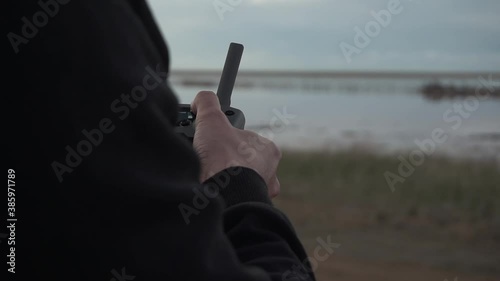 Drone remote controller. Pilot - operating quadcopter with remote controller and smartphone on sunset. Joysticks. Sticks close up. Close up hands with RC. 