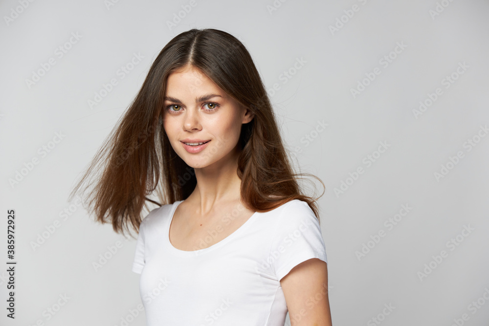 Charming brunette woman in a white t-shirt is looking ahead and her hair Charming brunette woman in a white t-shirt is looking ahead and her hair