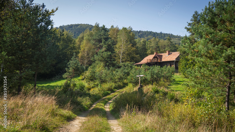 Wooden cottage house in forested mountains and hills area. Beskid Niski, Poland, Europe.