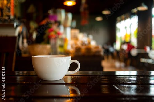 Hot Coffee Cup on Wood Table in blurred Coffee Shop background.