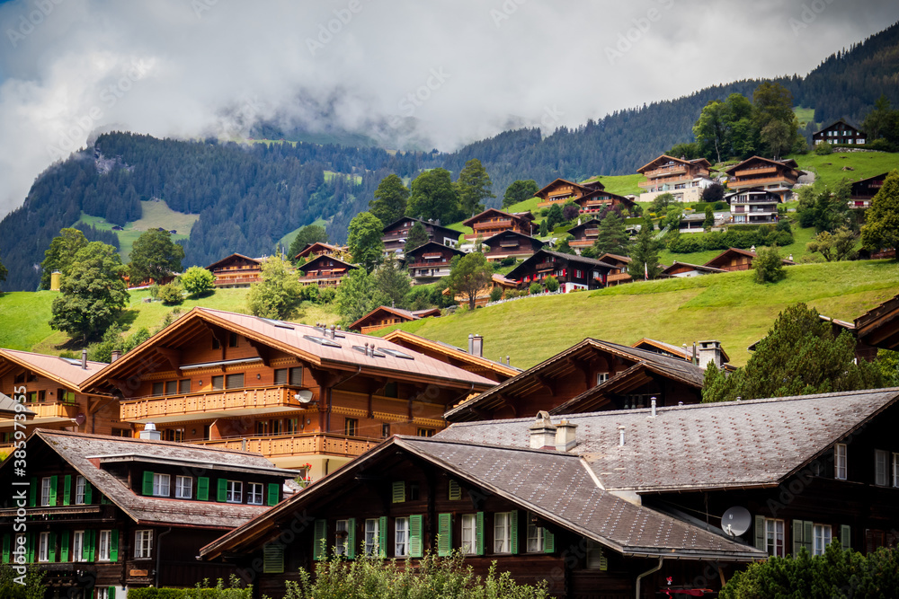 Rows of houses going up a hill in the Alps of Switzerland on a cloudy summer day. 