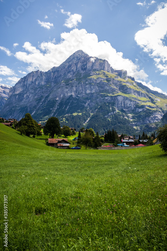 Village in a valley in the Alps of Switzerland with a mountain peak in the background on a summer day. 