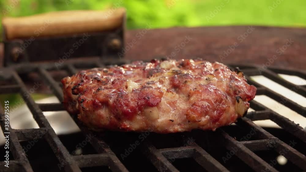 A delicious homemade meat cutlet for a burger is flipped on the grill grid A delicious homemade meat cutlet for a burger is flipped on the grill grid
