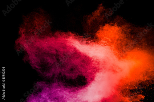 Red pink color powder explosion on black background.Freeze motion of red dust particles splashing.