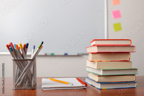 School supplies on a desk. Stack of books, notebook and many pencils laying on the table. Education, school, college, university.