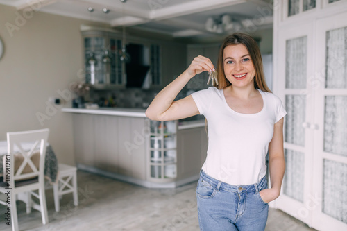 Young happy smiling business woman or real estate agent showing keys from new house