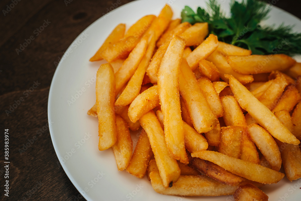 Fried potatoes in oil with herbs. Sliced golden slices with dill. Fast food on a white plate. Dish on a wooden table Fried potatoes in oil with herbs. Sliced golden slices with dill. Fast food on a white plate. Dish on a wooden table