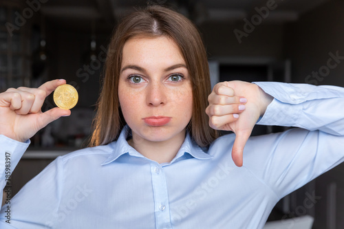Young business woman holding bitcoin with angry face  negative sign showing dislike with thumbs down