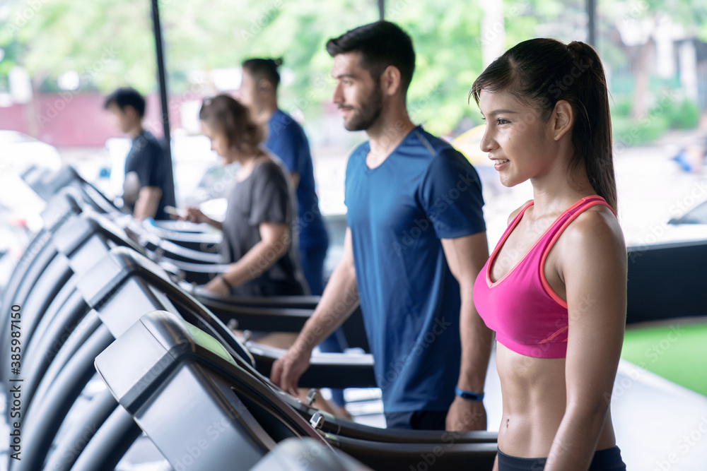 Group of people Walking on treadmill or running machine in modern fitness gym.