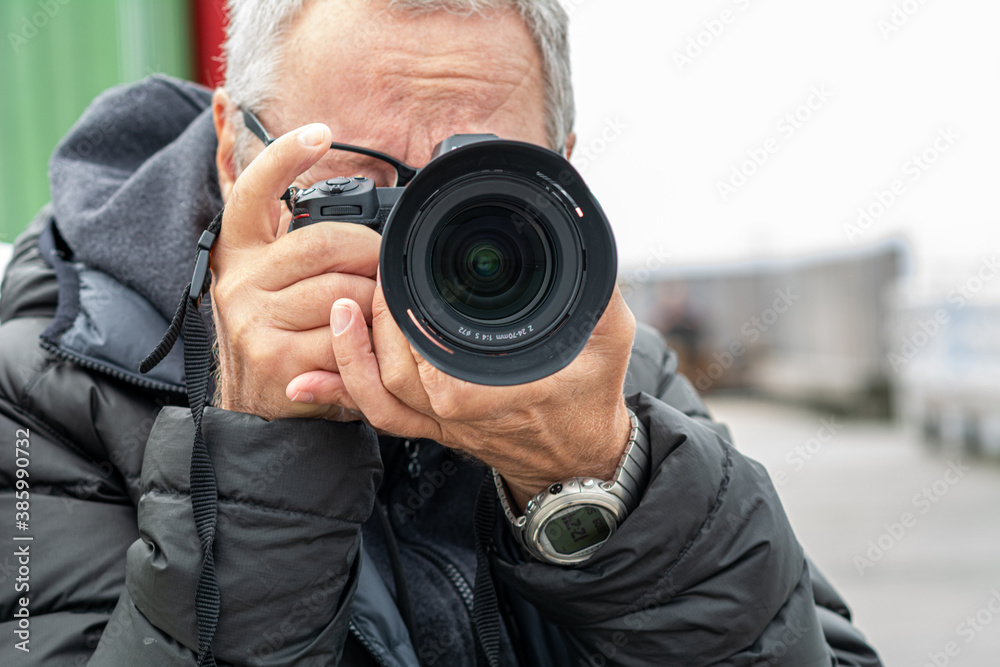 A closeup picture of a middle-aged man, in his 50s, taking pictures. Light and blurry background A closeup picture of a middle-aged man, in his 50s, taking pictures. Light and blurry background