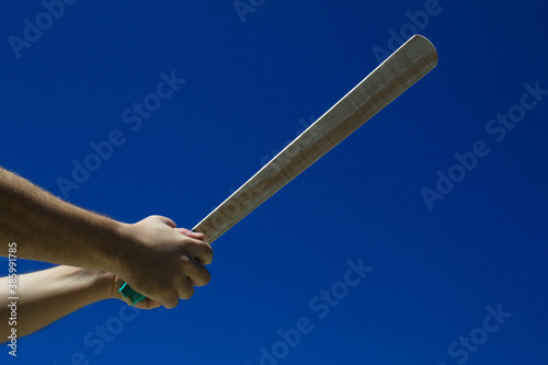 Taco de madeira com fundo do céu azul na mão de uma jogador
