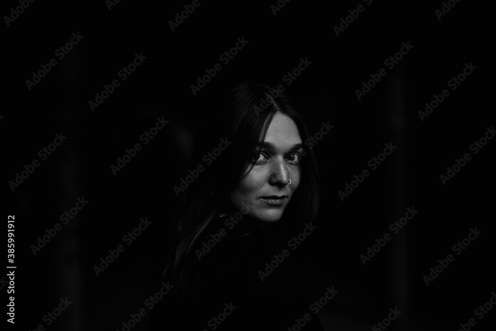 Moody black and white photo of young caucasian woman with pierced nose and no makeup. Youth lifestyle and fashion concept.