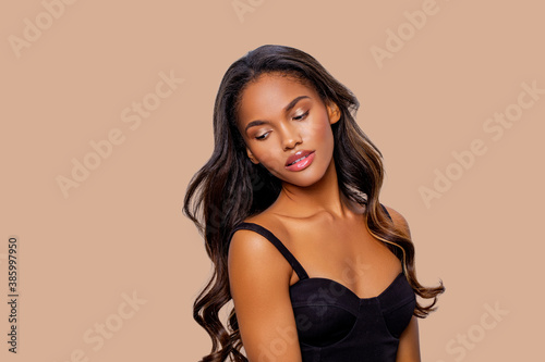 Beauty styled portrait of a young African - American woman. Fashion African - American girl with curly hair posing in the studio on a beige background. isolated. Studio shot.   