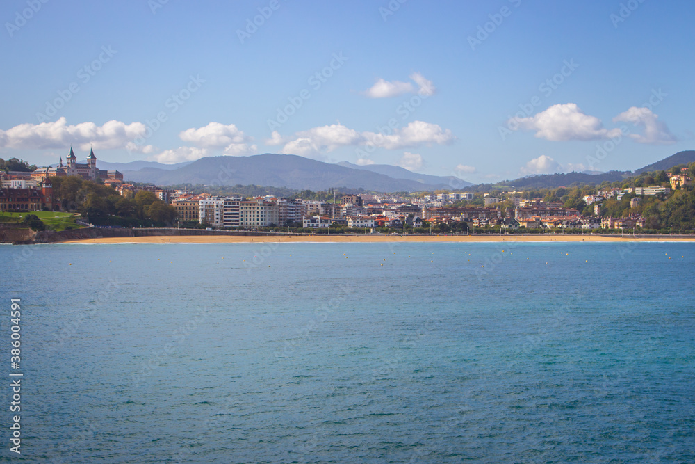Fototapeta premium San Sebastian landmark, view from the sea. Famous beach called La Concha in San Sebastian, Spain. Scenic bay of Biscay. Aerial view of Biscayen seacoast and mountains on background. Seaside and city.