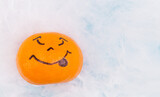 Bright orange Halloween scary tangerine emotion face on white spider web background, selective focus